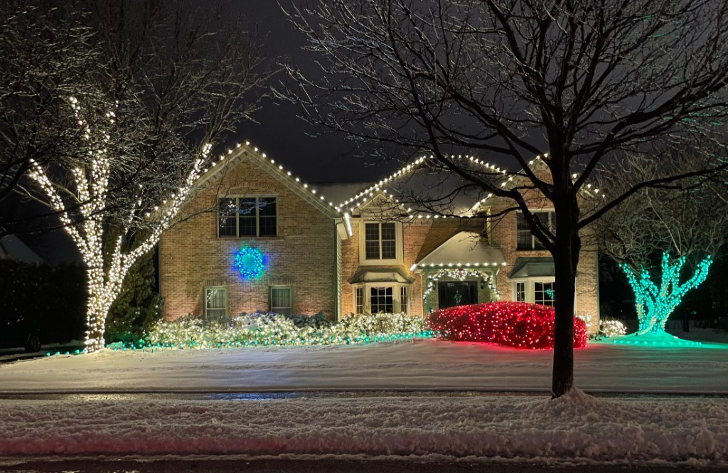 Colorful landscape and roofline holiday lighting on a brick home