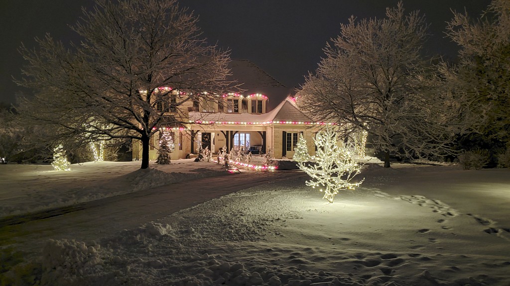 Snow covered home with pink and white holiday lighting