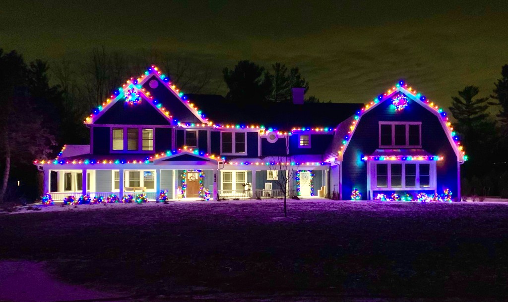 Farmhouse outlined with multicolor Christmas lights at night
